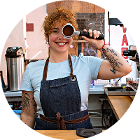 Barista mujer sonriente mostrando portafiltro en cafetería artesanal