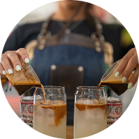 Barista sirviendo bebidas frías en vasos de vidrio con leche y café